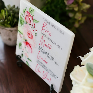 a close up of a sign on a table with flowers