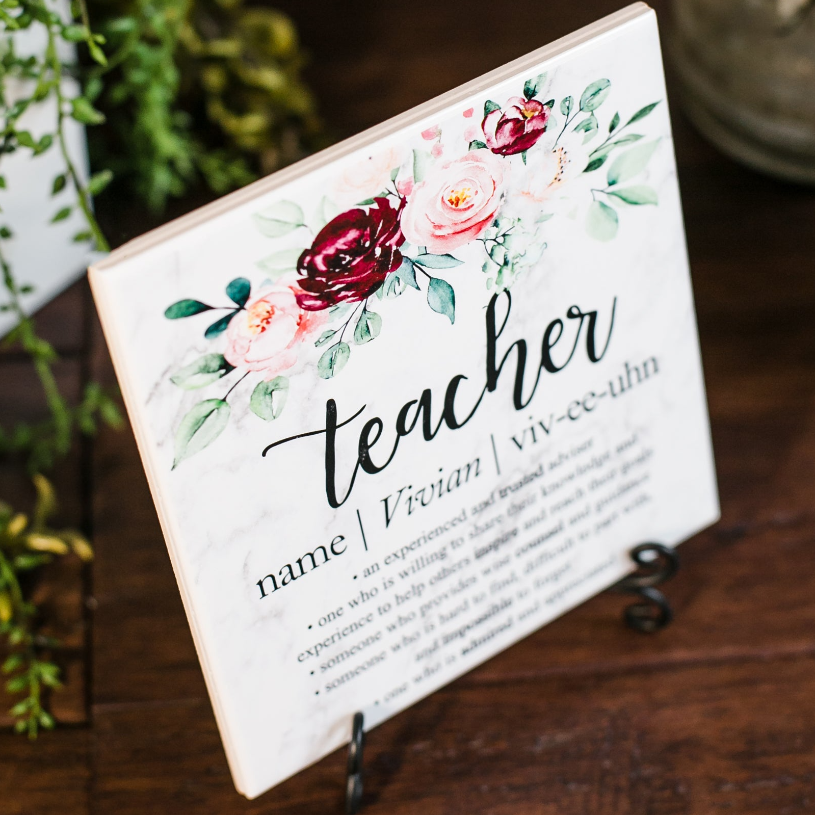 a sign that says teacher next to a potted plant