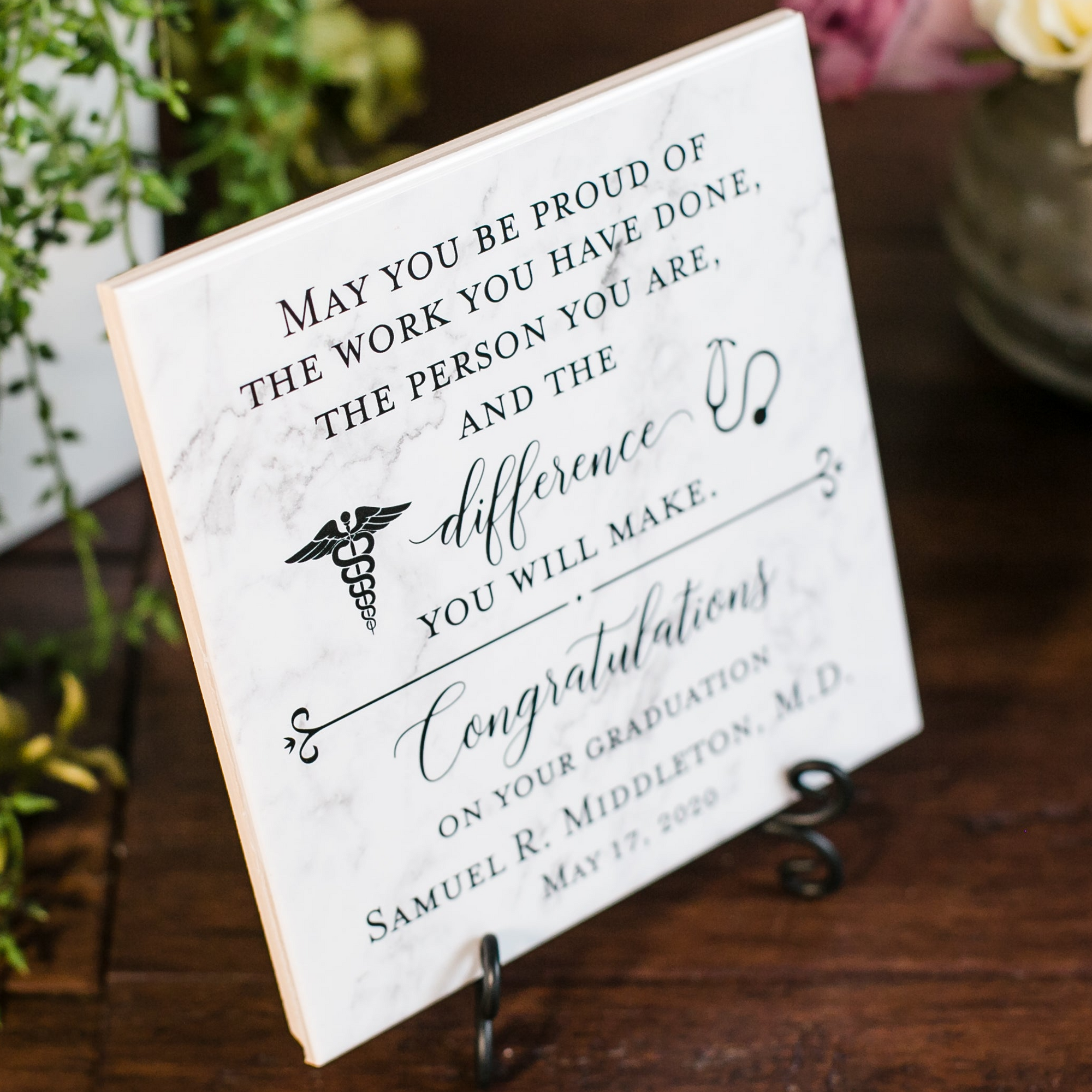 a sign on a table with flowers in the background